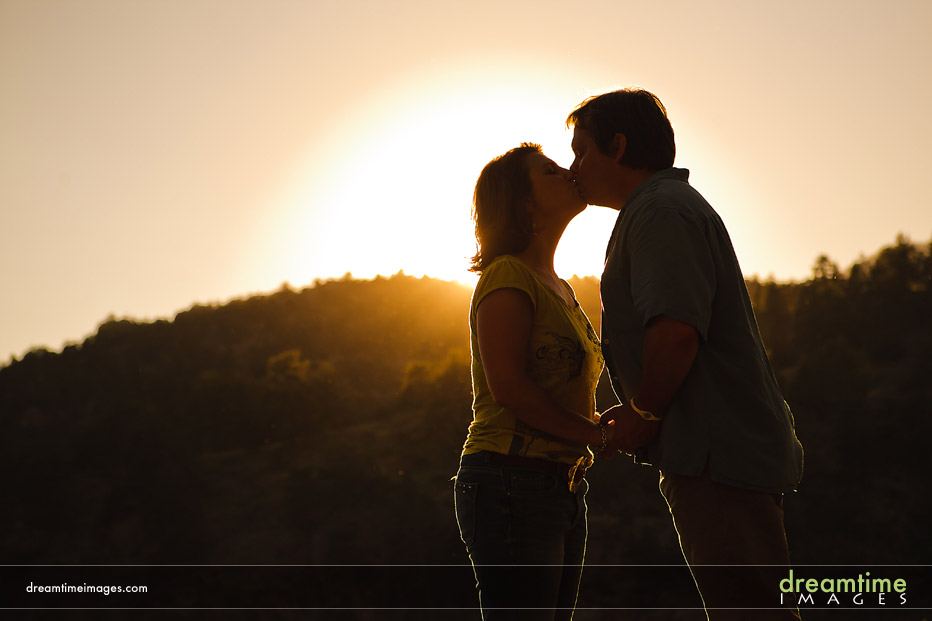 couple kissing in front of sun
